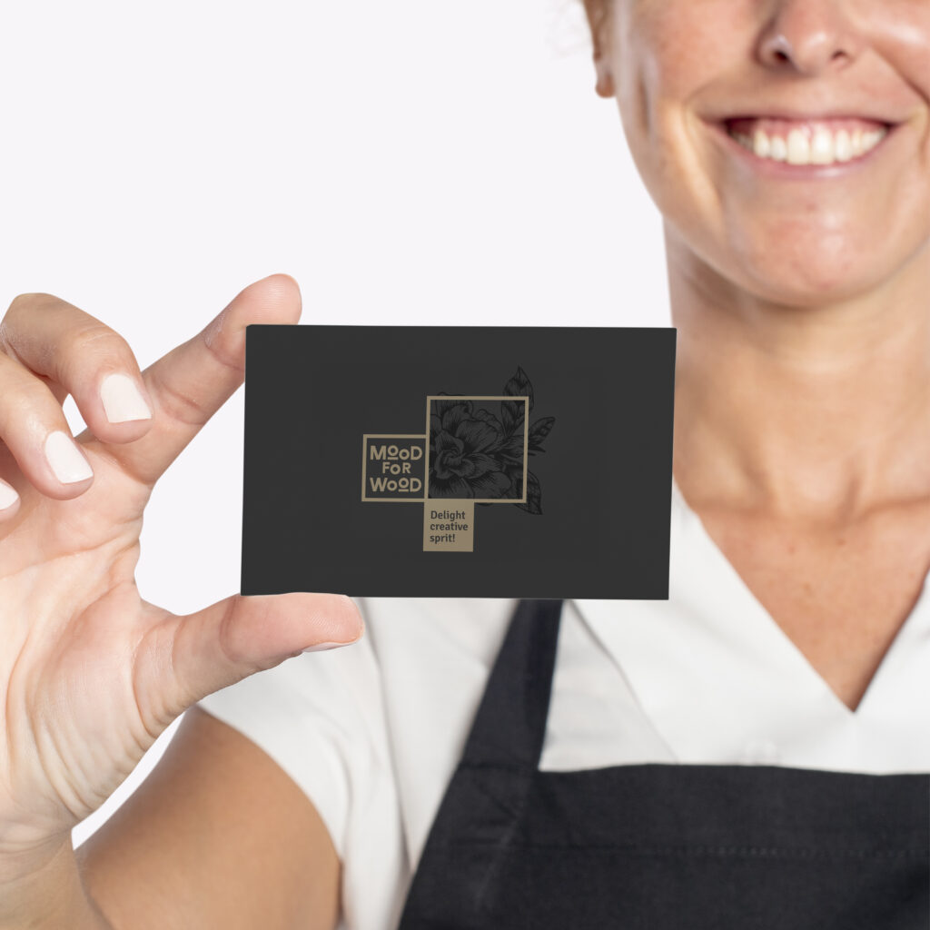 Person holding a black and gold Mood for Wood business card — brand identity and logo design by Creative Lab
